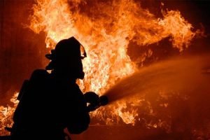 Firefighter extinguishing fire using foam