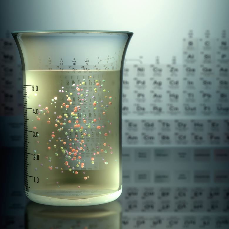 Periodic table and substance with trace elements in a glass beaker