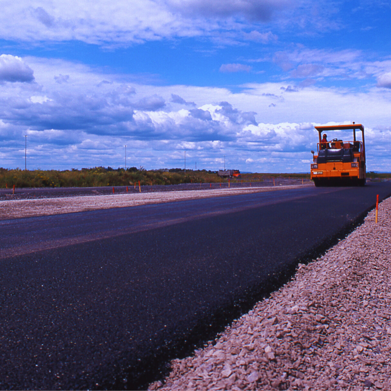 Vägvält som lägger färsk asfalt på en nybyggd väg.