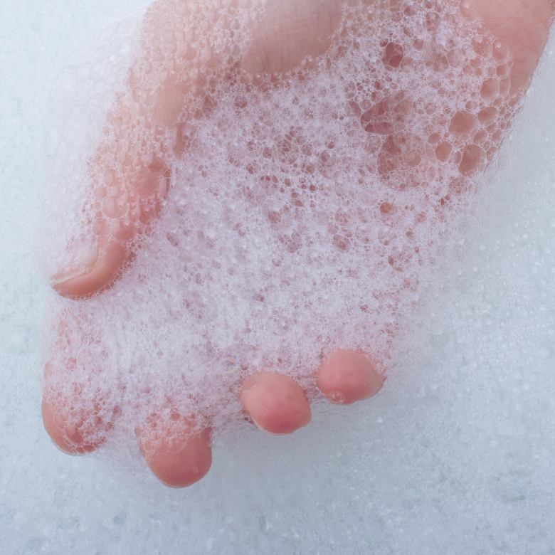 Elin sabun veya duş jelinden çıkan beyaz köpüğü tuttuğu yakın çekim görüntü.