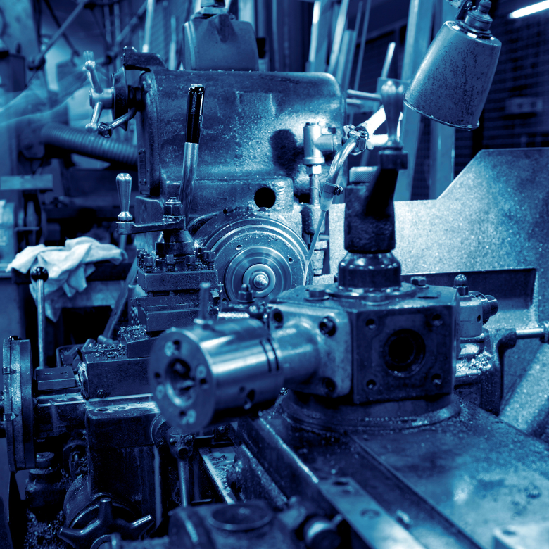 Nahaufnahme einer industriellen Werkzeugmaschine in einer Werkstatt, gehalten in kühlen Blautönen.